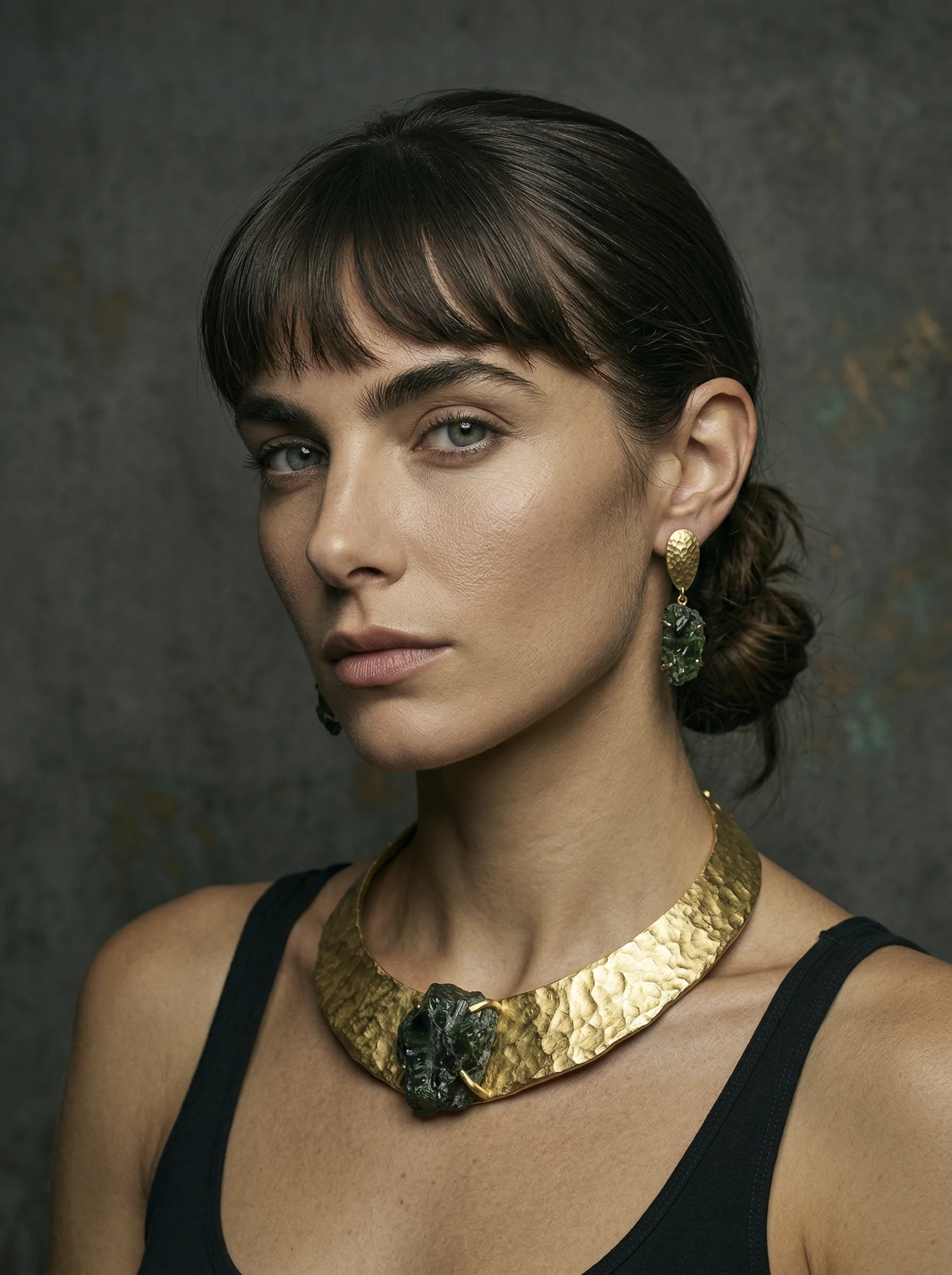 Portrait éditorial : collier sculptural et boucles d’oreilles en or et pierres vertes.